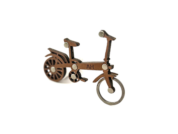 Medium Brown leather bicycle-shaped keychain with initials on a white background